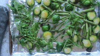 a baking tray with brussels sprouts, asparagus and green beans on it