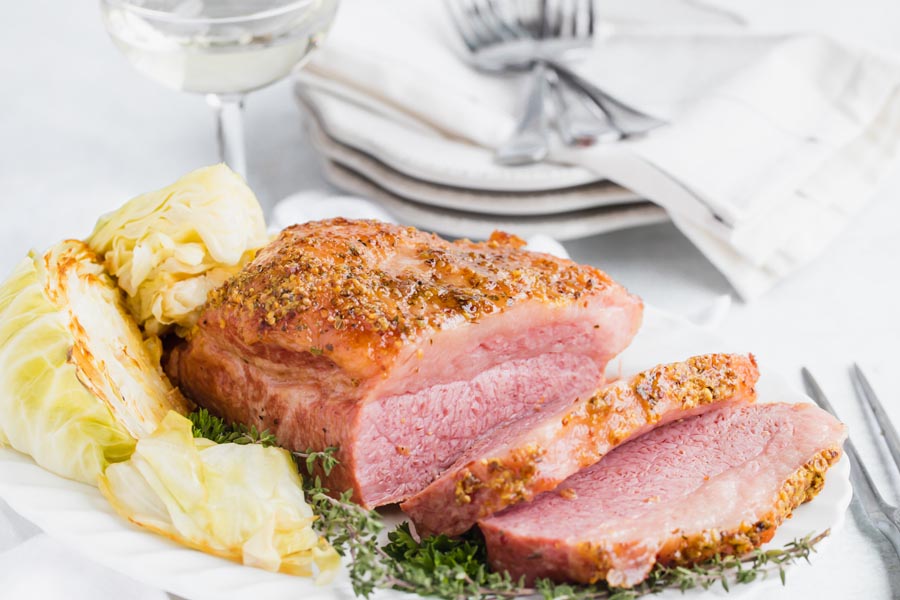 sliced beef on a platter next in front of a stack of plates and forks