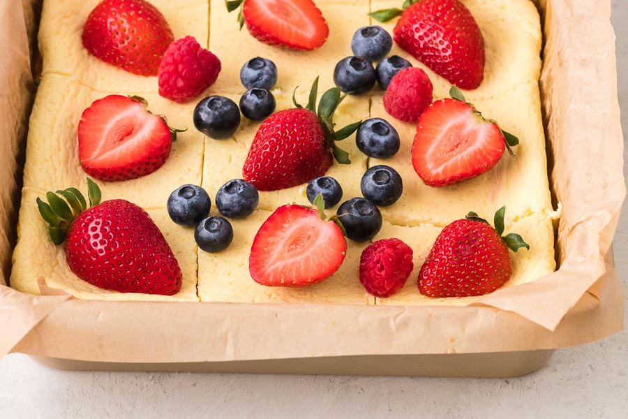 Baked Greek yogurt cut into squares and topped with fresh strawberries, blueberries, and raspberries.