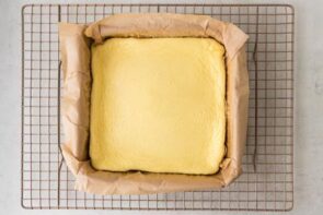Baked yogurt cooling in a parchment-lined square pan on a wire rack.