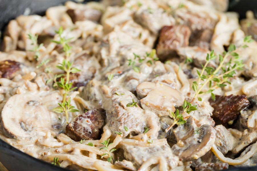 creamy beef noodles in a skillet covered with thyme