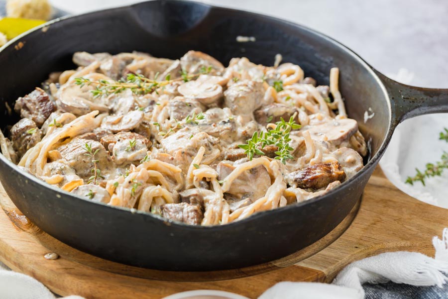 a skillet with steak bites, noodles and mushroom in a cream sauce