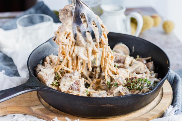 pulling out a serving of noodles with beef and mushrooms