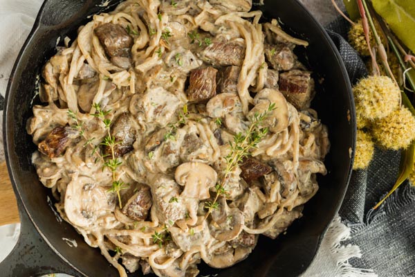 a cast iron skillet with beef noodles in it