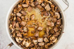 mushrooms and steak bites in a skillet with broth