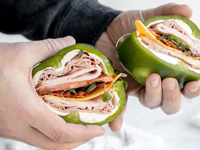 holding two bell pepper sandwiches in hands