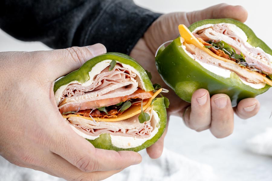 holding two bell pepper sandwiches in hands