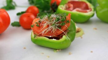 a half of a bell pepper with a tomato slice and sprouts on top