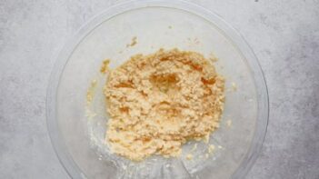 a clear bowl containing wet ingredients of butter and egg