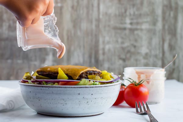 thousand island dressing being poured on big mac salad