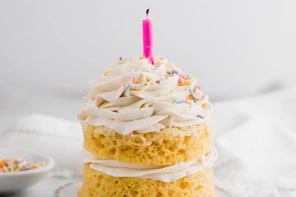 a pink candle stuck into a vanilla cake with white frosting