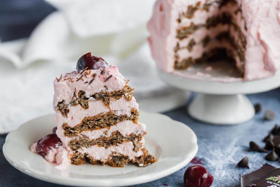 a slice of waffle cake four tiered with pink frosting and cherries