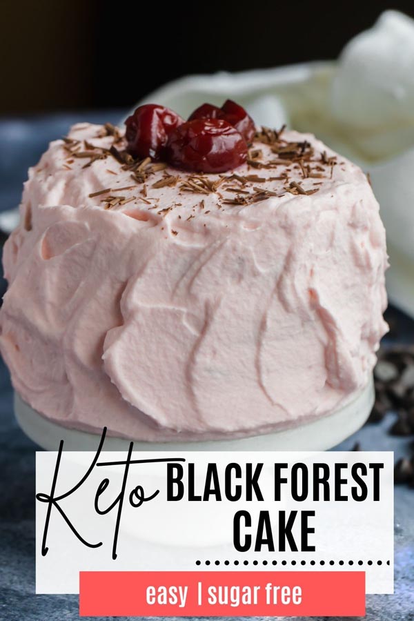 a small cake with pink frosting, shaved chocolate and cherries on top