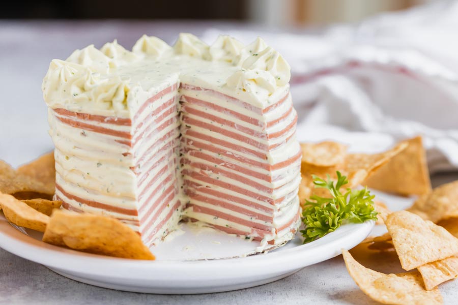 A slice out of a cake made out of bologna and cream cheese.