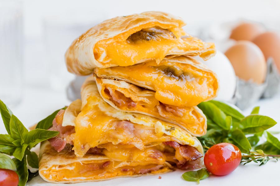 a leaning stack of breakfast quesadillas filled with oozing cheese