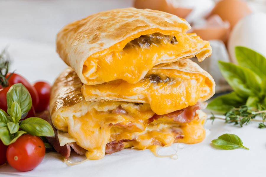 cheddar cheese drips down from a stack of tortillas