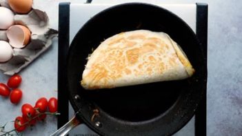 a folded quesadilla cooking on a skillet