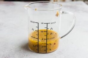 A measuring cup with a zesty Italian vinaigrette inside.