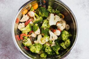 Raw broccoli, cauliflower and other ingredients tossed together in a bowl.