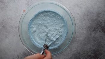whisking a blue ice cream base with a whisk