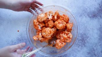 a bowl with buffalo sauce coated all over cauliflower florets