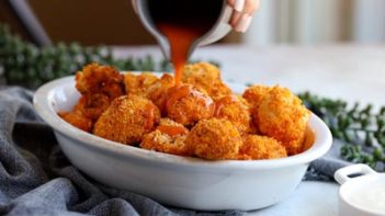 pouring buffalo sauce on roasted cauliflower bites