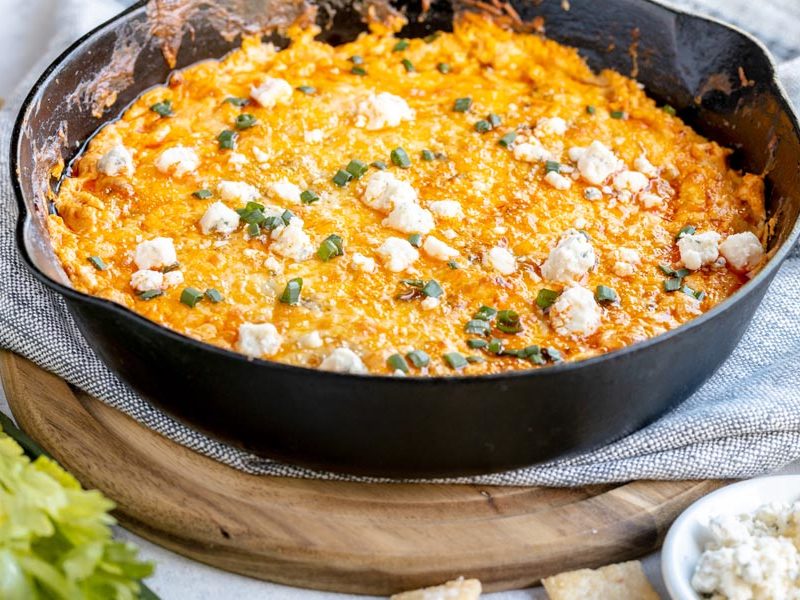 a large skillet with cheesy dip topped with chives and cheese