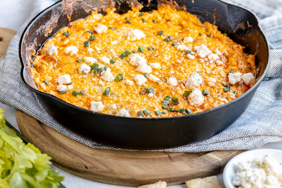 a large skillet with cheesy dip topped with chives and cheese