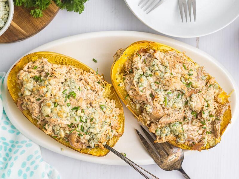 A plate of buffalo chicken stuffed in a spaghetti squash and topped with chives.