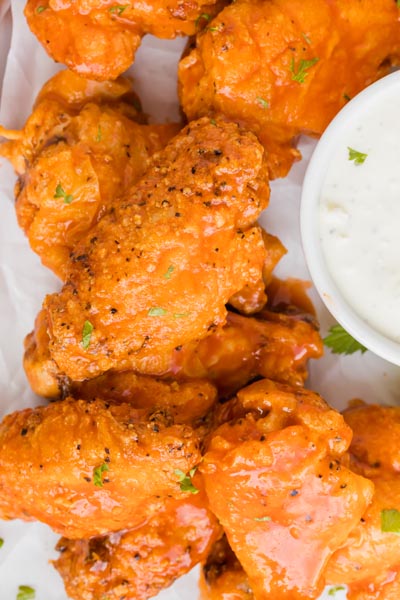 Chicken wings baked and coated with buffalo sauce and topped with black pepper and minced parsley.