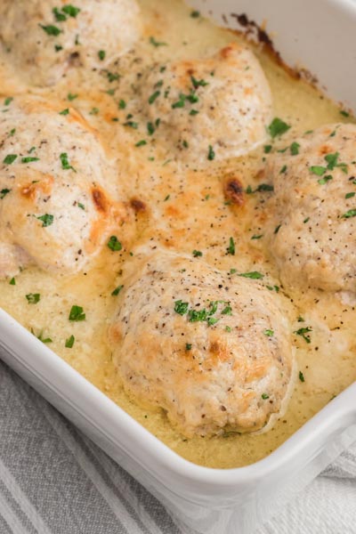 A chicken casserole with creamy white caesar sauce and topped with chopped parsley.