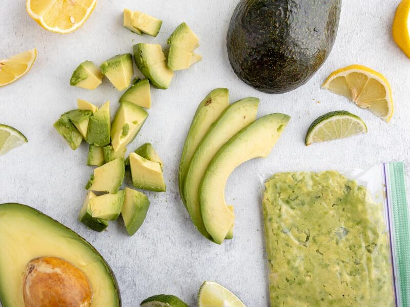 spread of diced avocado, sliced avocado, lemon and lime wedges and a baggie with mashed avocado inside