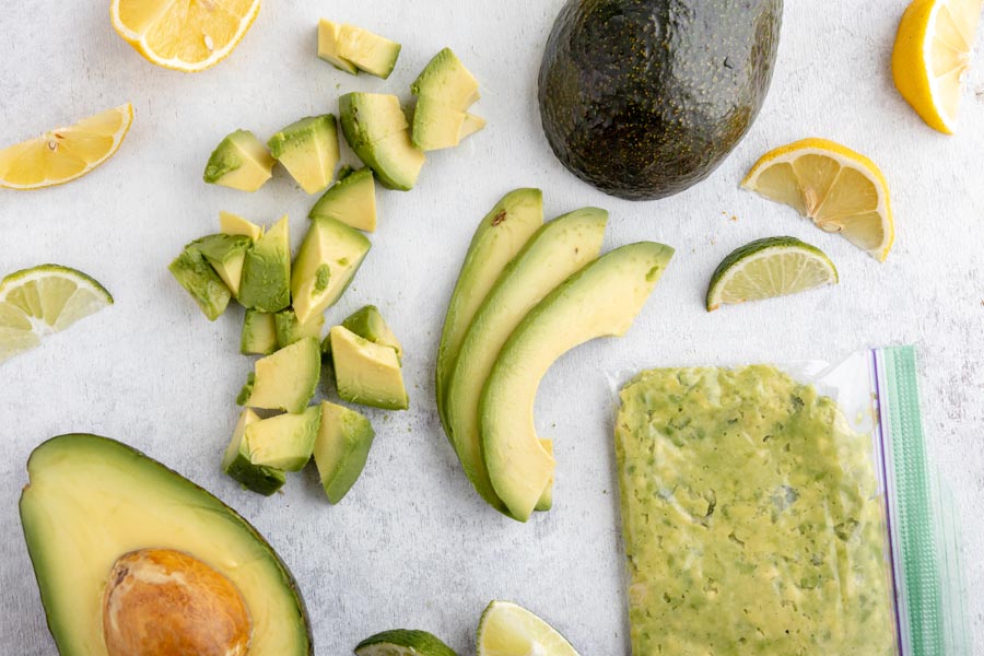 spread of diced avocado, sliced avocado, lemon and lime wedges and a baggie with mashed avocado inside