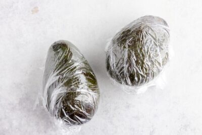 two whole avocados wrapped in plastic wrap