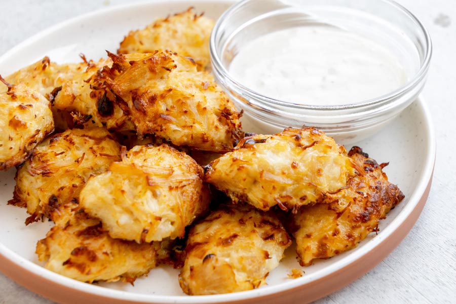 Golden canned chicken nuggets served with a side of creamy ranch dipping sauce on a white plate.