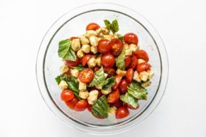 a glass bowl with a caprese salad tossed in it
