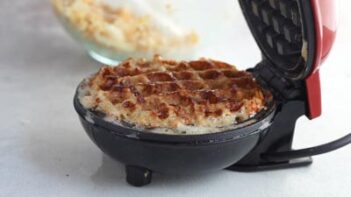 A waffle cooking in a waffle maker.