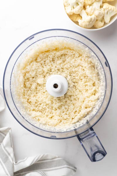 A food processor bowl with freshly processed cauliflower rice.