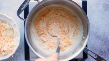 stirring shredded cheese into a saucepan