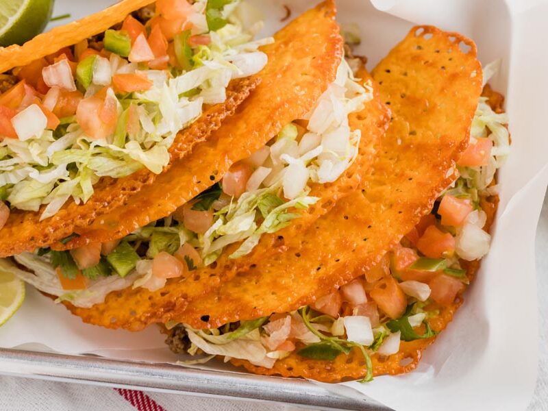 Crispy keto tacos on a tray stacked up on each other.