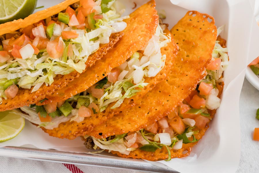 Crispy keto tacos on a tray stacked up on each other.