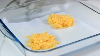 Two piles of cheese in a parchment lined baking tray.