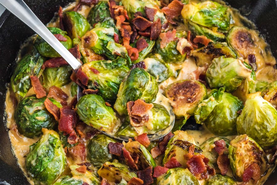 A spoon holding creamy brussels sprouts side dish.