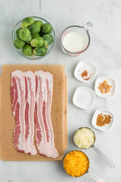 Ingredients for a brussels sprouts gratin dish with raw bacon strips and whole brussels sprouts.