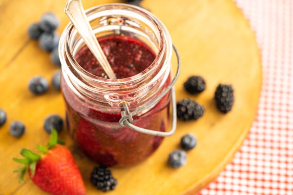 berry jam with a spoon in the jar next to berries