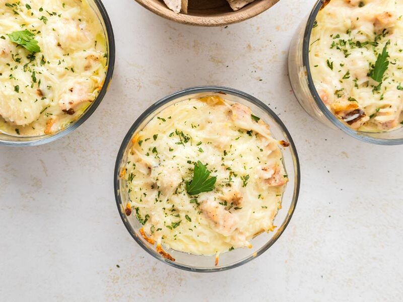 Overhead view of baked chicken Alfredo lasagna bowls topped with melted cheese and parsley.