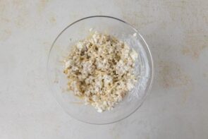 A bowl of cottage cheese mixed with shredded cheese and seasoning for the lasagna filling.