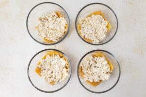 Cottage cheese mixture spooned over lasagna noodles in four individual bowls.
