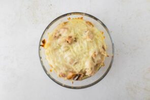 A fully baked chicken Alfredo lasagna bowl topped with melted mozzarella.