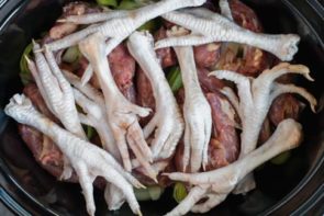 chicken neck and chicken feet in a slow cooker base for bone broth